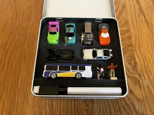 A carousel photo displaying 'Deluxe cars inserted inside the V.I.A. Metal Tin' out of an array of 'Deluxe Cars', at full size. There's Batmobile, Rat Rod and Delorean Time Machine fitted into vehicle slots.