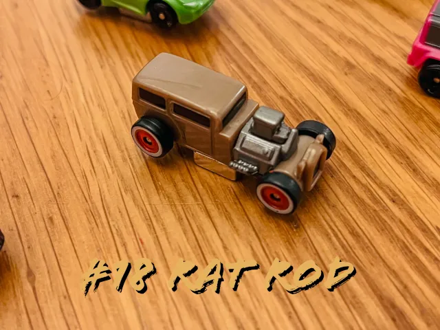 A carousel photo displaying the eighteenth vehicle named 'Rat Rod' out of an array of 'Deluxe Cars', at full size. The car is painted brown with red inner and black outer wheels.