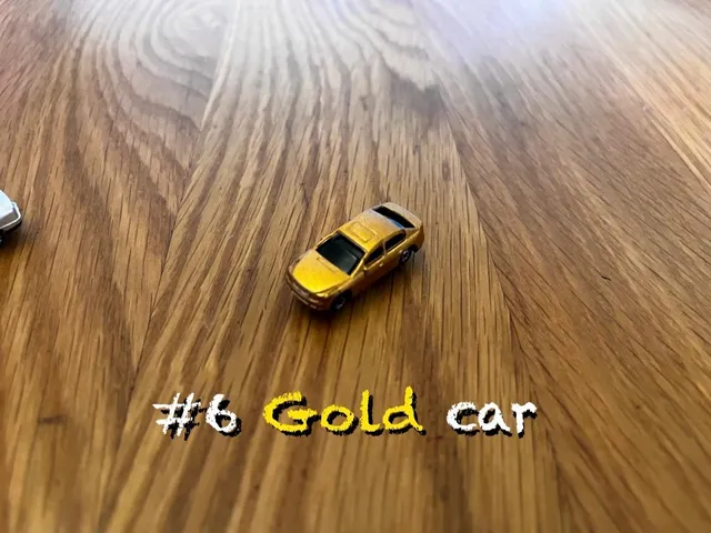 A carousel photo displaying the sixth car named 'Gold car' out of an array of V.I.A. 'mini Standard cars', at mini size. The car is painted gold with a standard SUV design.